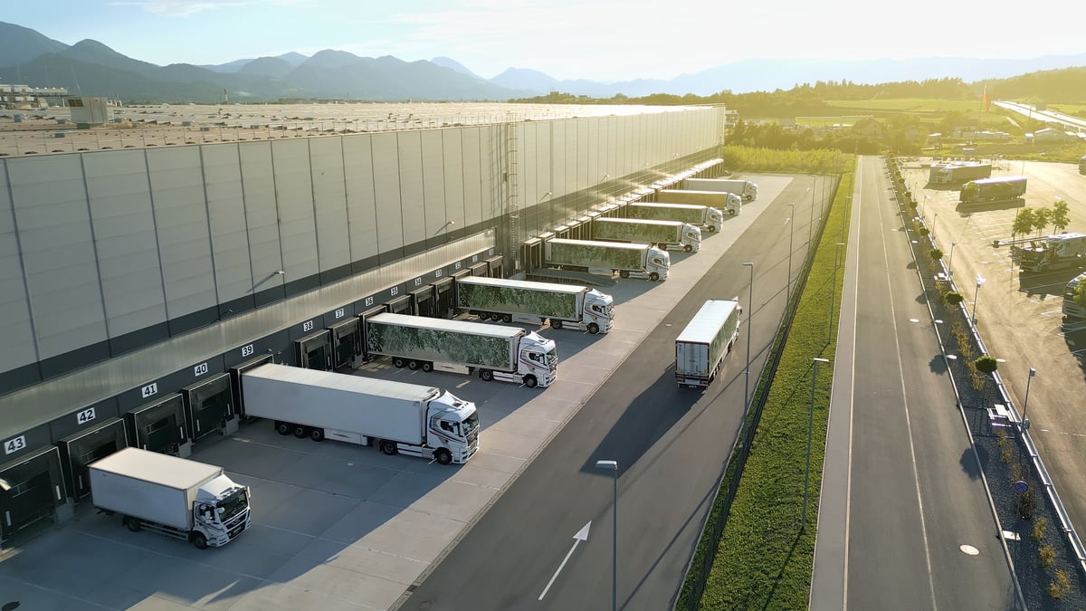 Vista aérea de nave de distribución industrial con andenes de carga y tráilers alineados