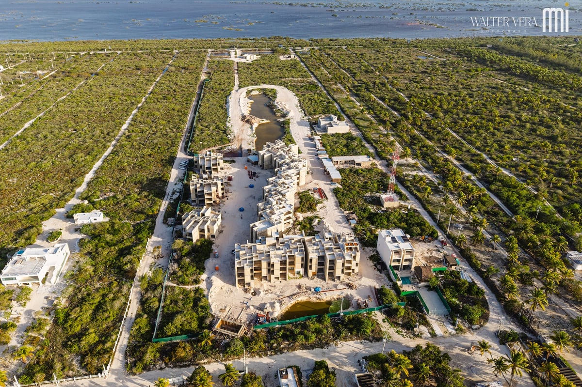 Vista aérea del proyecto AWAH Oasis de Mar en construcción, con estructuras en el centro, laguna y vegetación circundante. Junio 2026.