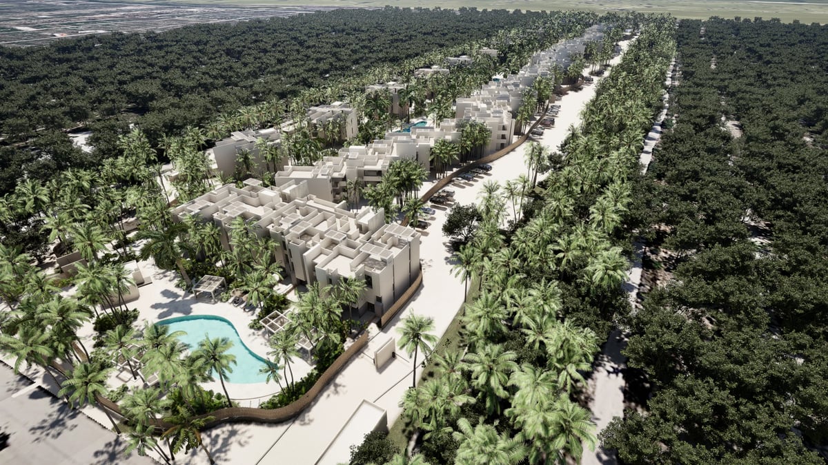 Aerial view of a planned residential development with modern buildings, palm trees, and green spaces integrated into a forested landscape