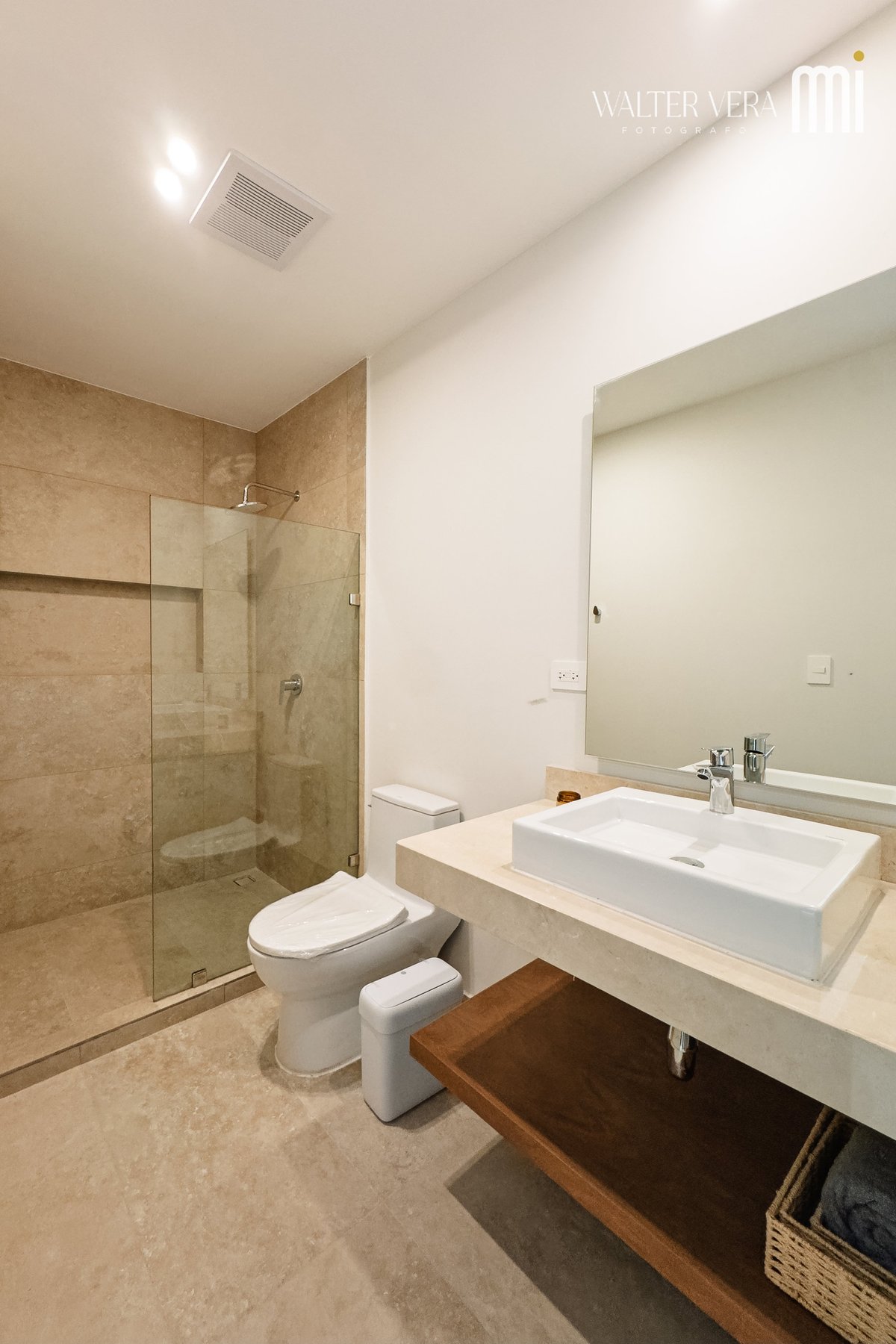 Modern bathroom with beige tile shower, white rectangular sink on floating vanity, toilet, and ceiling recessed lighting