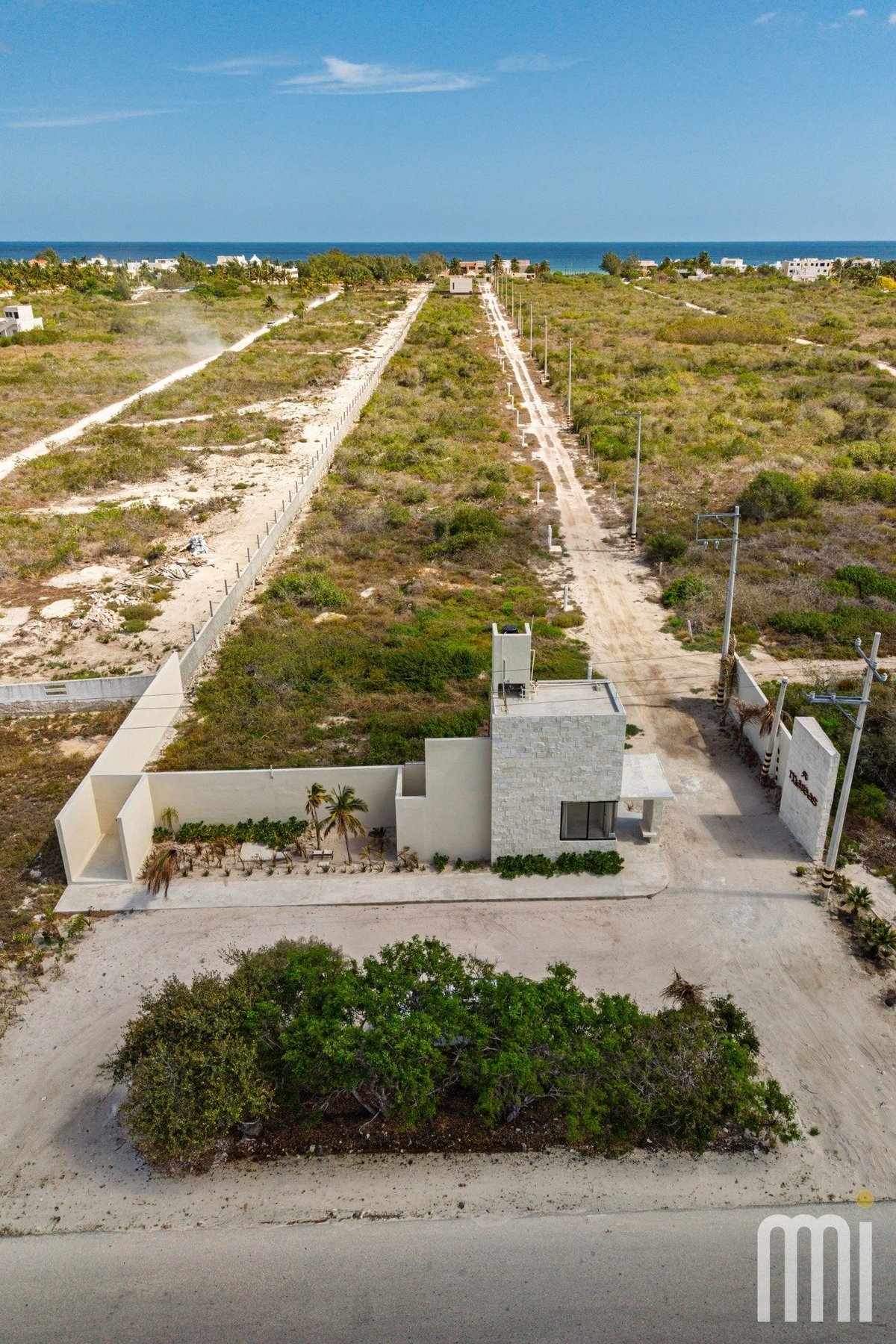Vista aérea de casa moderna sobre lote amplio con horizonte oceánico