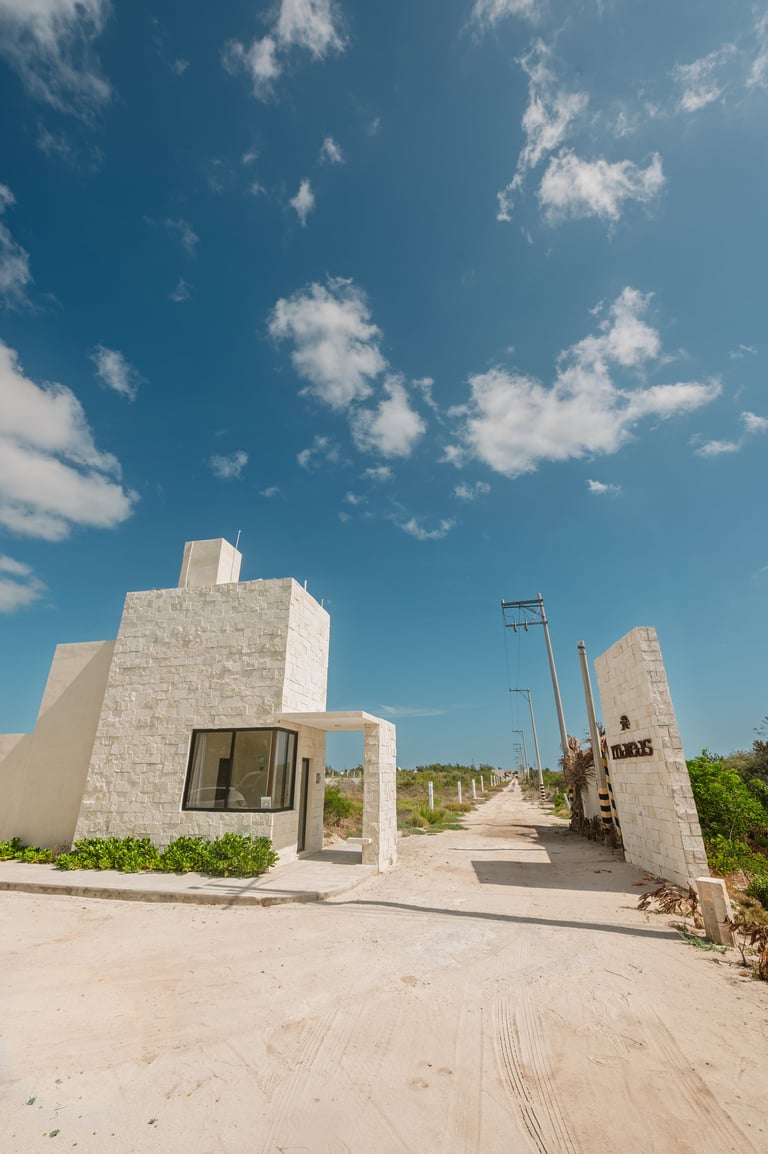 Edificio moderno de concreto blanco junto a un camino de arena bajo cielo despejado